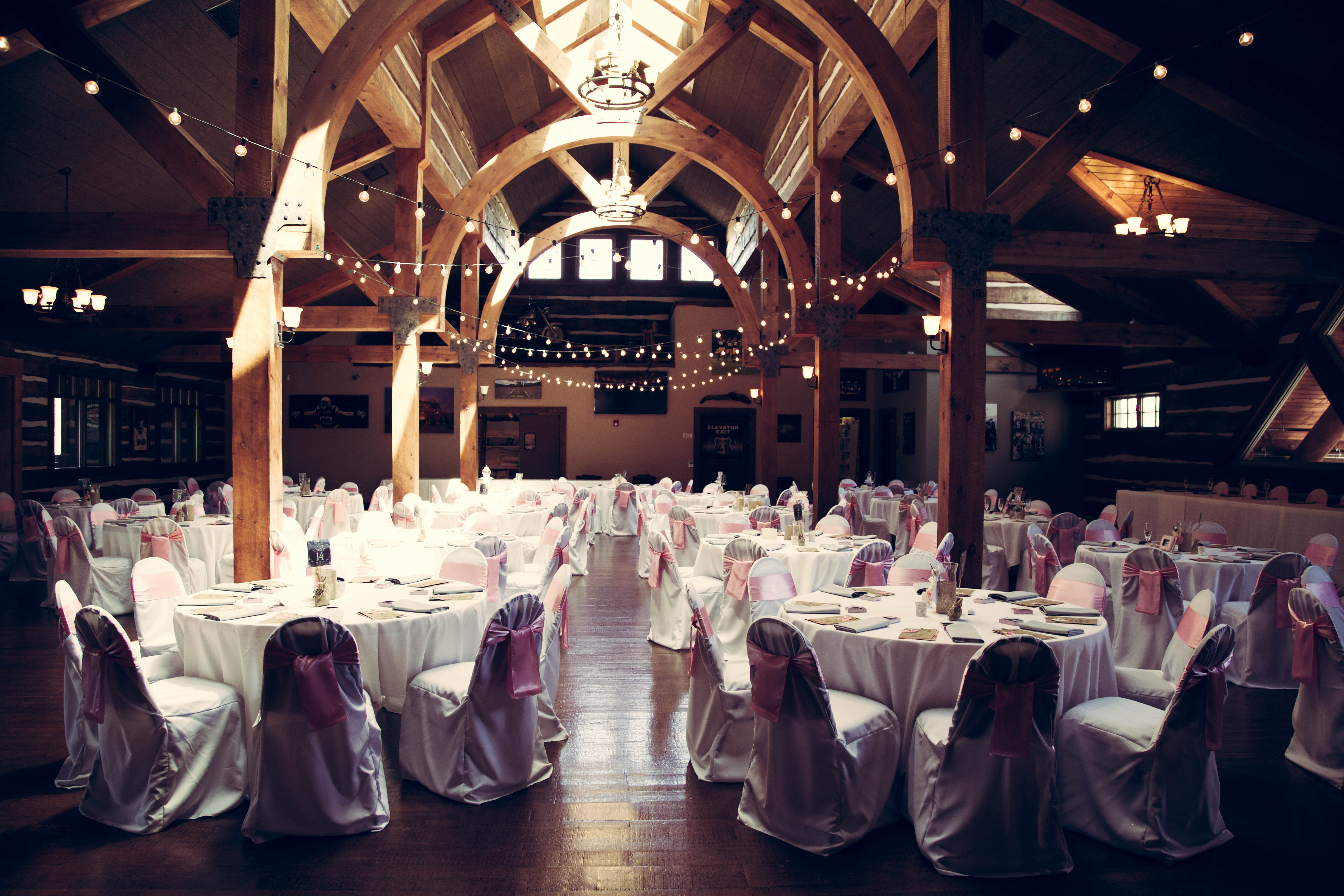 Elegant wedding reception setup with white chair covers and soft lighting.