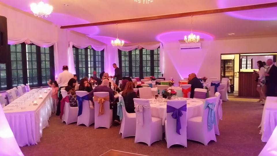 Elegant event setup with purple lighting and decorated chairs in a spacious room.