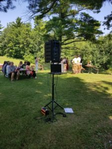 Outdoor event with speaker and seated guests.